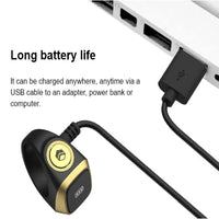 Black and gold smart ring charging via USB cable to laptop, long battery life